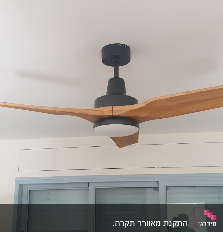 מאוורר תקרה עם כנפיים מעץ מותקן על תקרה לבנה